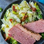 Corned beef with sauteed cabbage on a black plate.