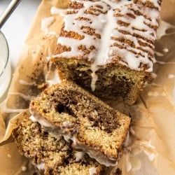 A sliced loaf of Cinnamon Swirl Bread on a sheet of parchment paper.