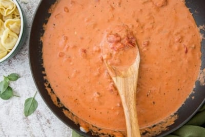 Tomato Cream Sauce in a skillet with a wooden spoon.