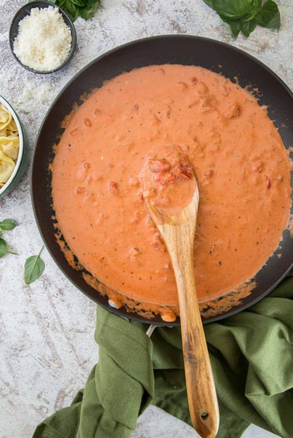 Tomato Cream Sauce in a skillet with a wooden spoon.