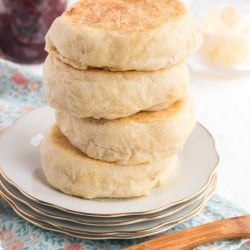 A stack of four English muffins on a plate.