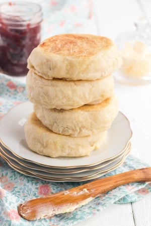 A stack of four English muffins on a plate.