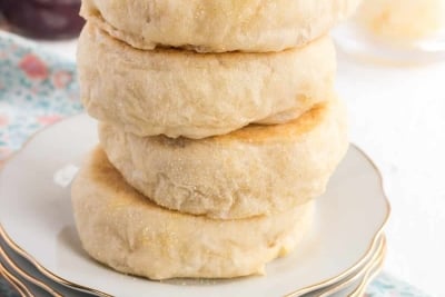 A stack of four English muffins on a plate.