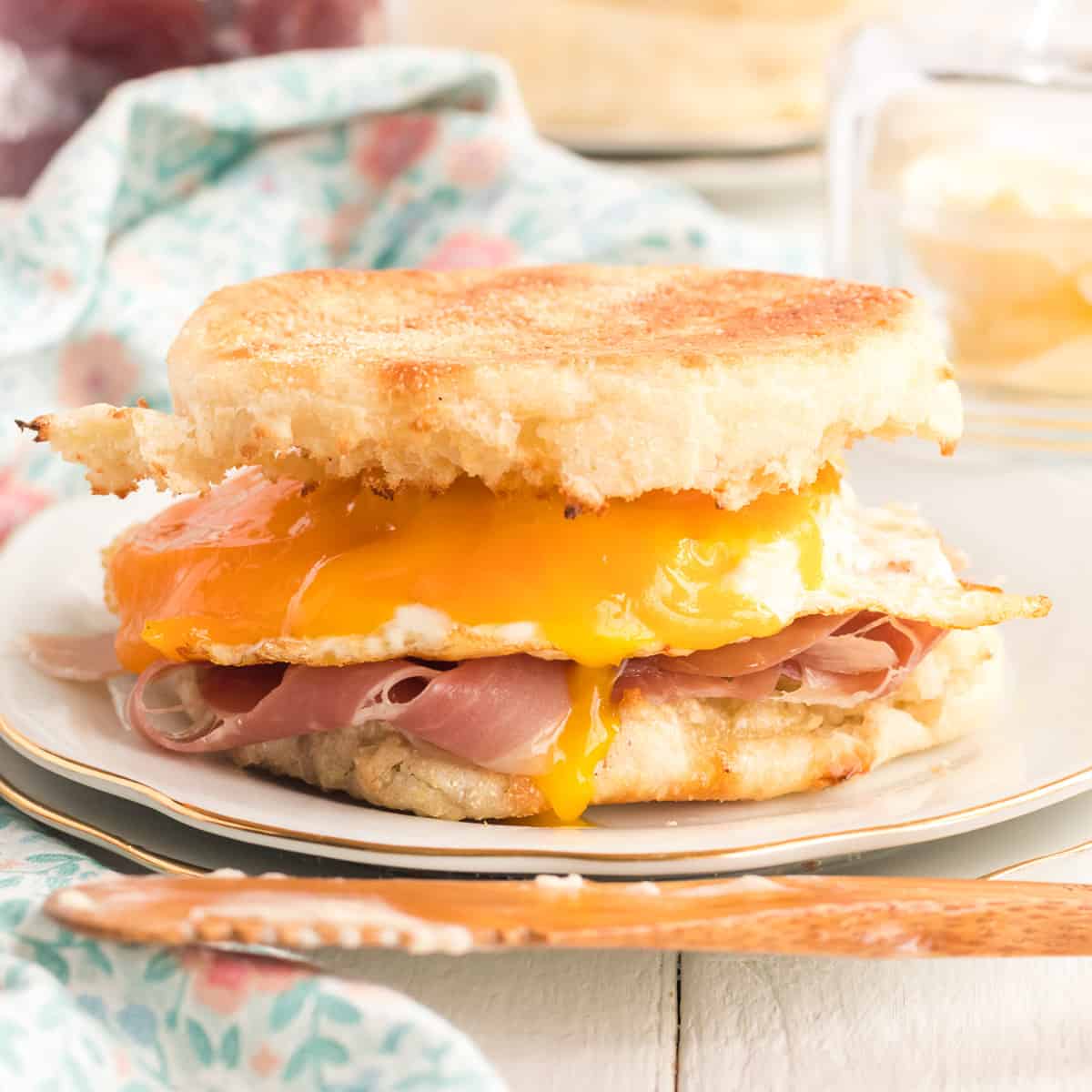 A breakfast sandwich made with egg, ham and cheese on a toasted English muffin.