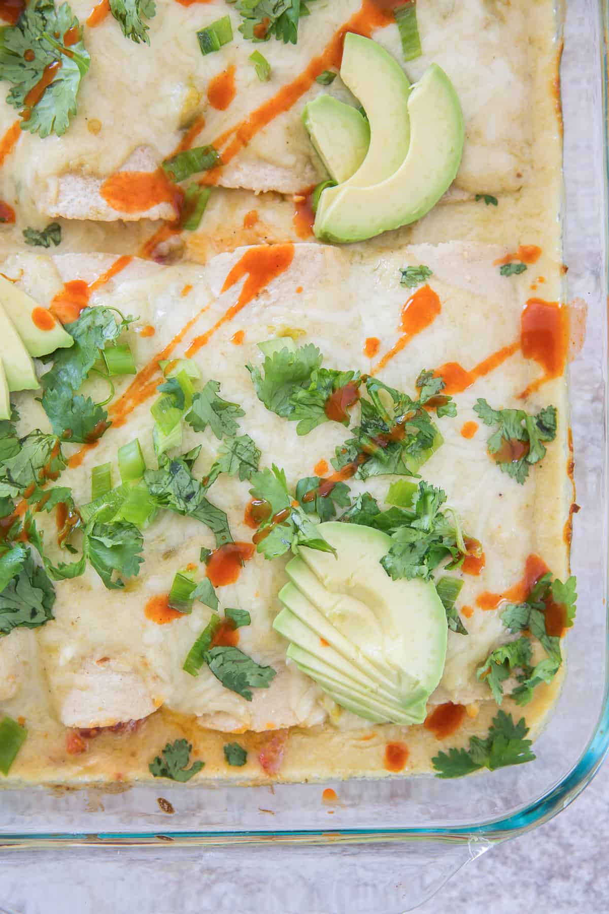 A closeup over the top image of Sour Cream Chicken Enchiladas in a casserole dish.