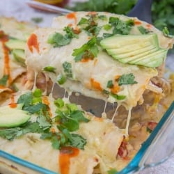 A spatula lifts enchiladas from the dish with hot sauce in the background.