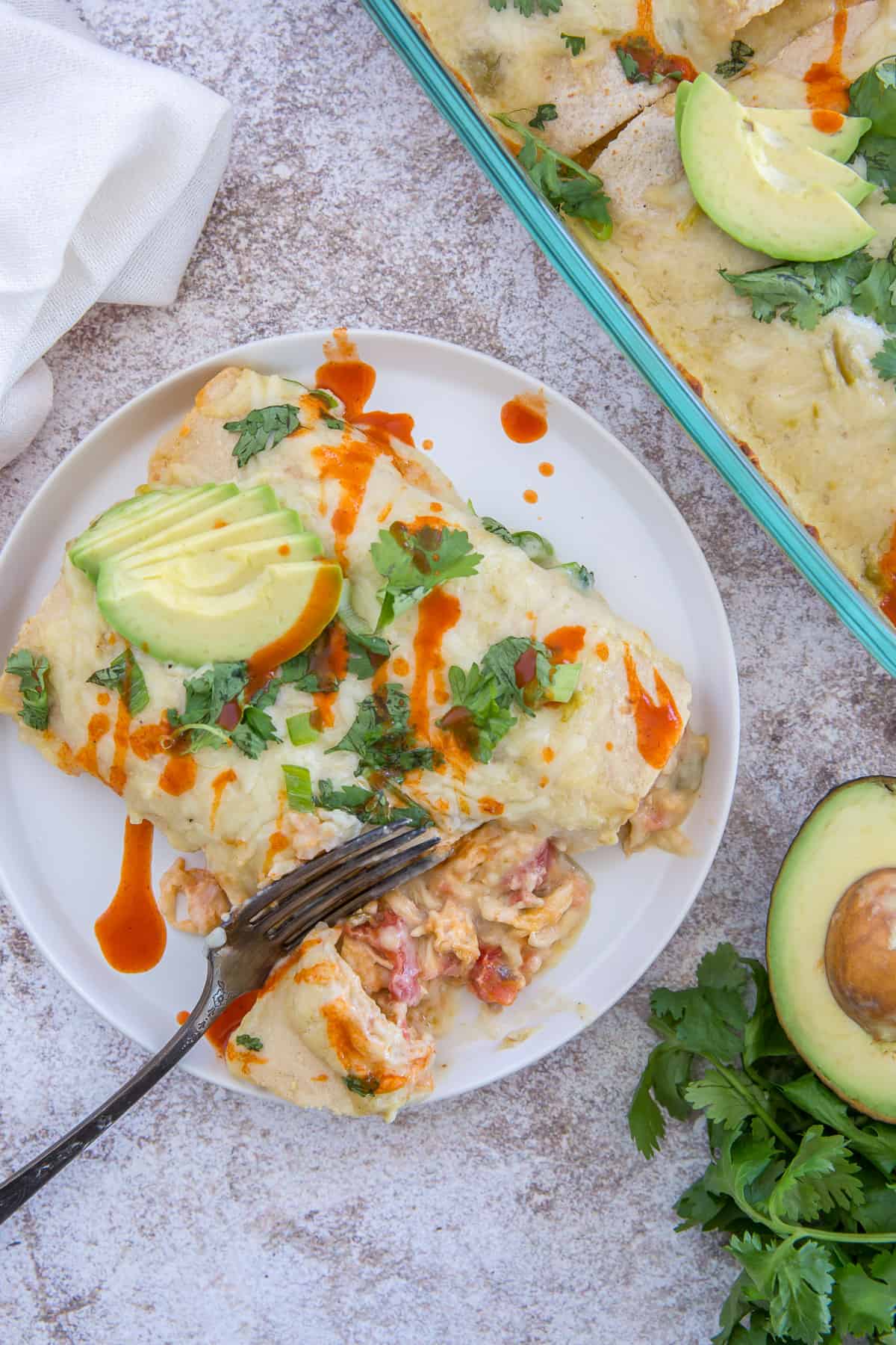 A fork breaks into a serving of Sour Cream Chicken Enchiladas.