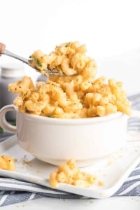 An individual serving of Stovetop Macaroni and Cheese being scooped up with a fork from a small white bowl.