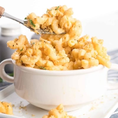 An individual serving of Stovetop Macaroni and Cheese being scooped up with a fork from a small white bowl.