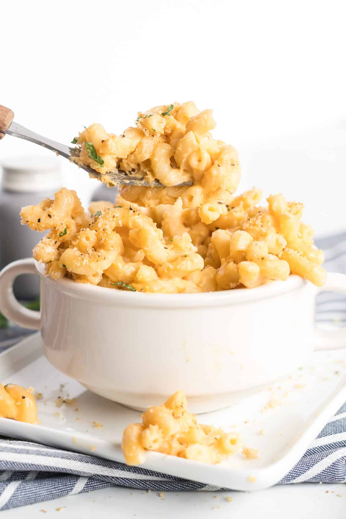 An individual serving of Stovetop Macaroni and Cheese being scooped up with a spoon from a small white bowl.