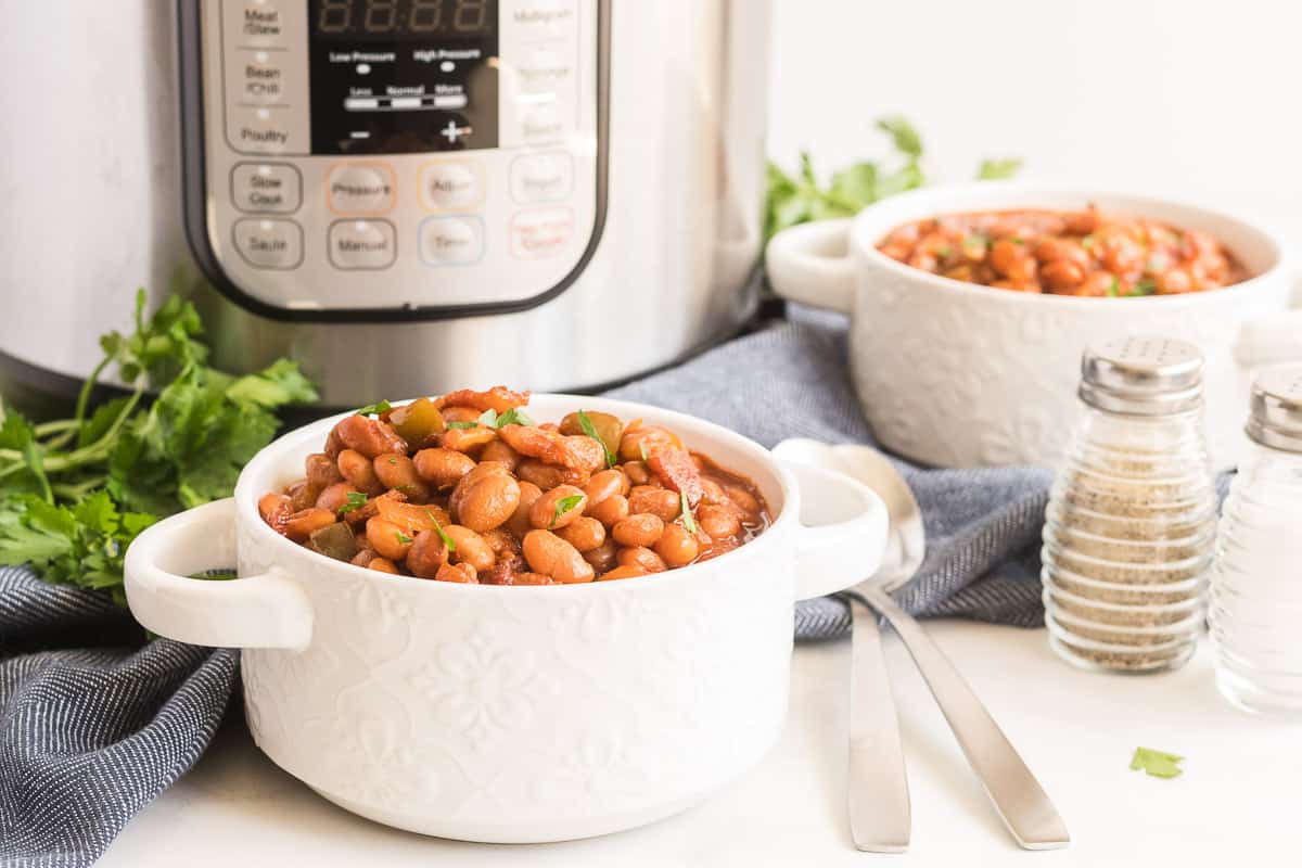 Two white bowls filled with baked beans sit in front of an Instant Pot.