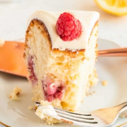 A slice of Lemon Raspberry Bundt Cake on a white place with a fork.