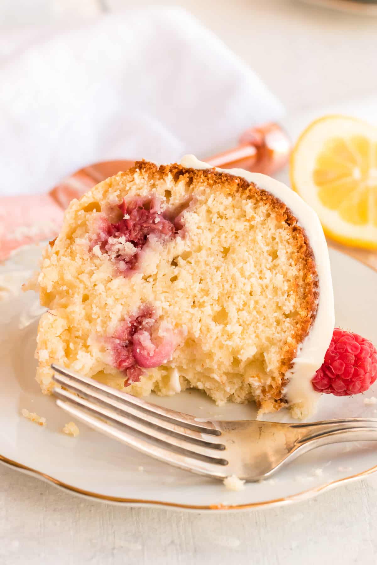 A slice of Lemon Raspberry Bundt Cake on a white plate with a fork.