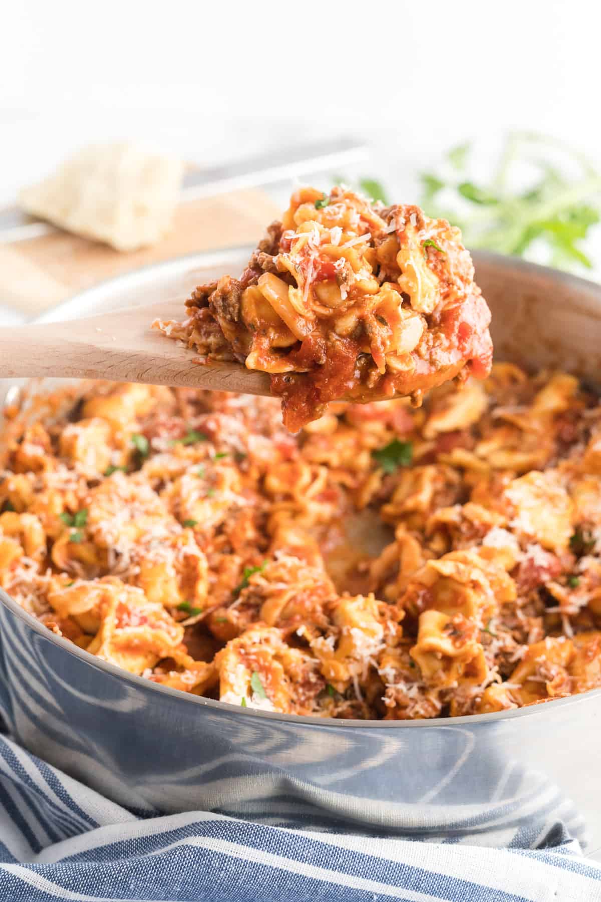 A spoon lift some of the meaty tortellini from the skillet.