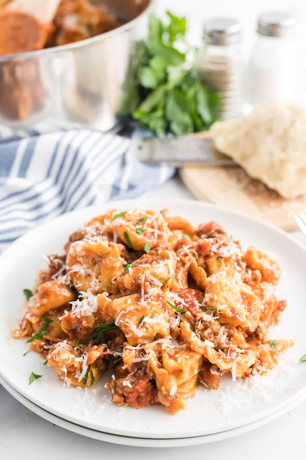 Tortellini on a white plate with a blue striped cloth in the background.