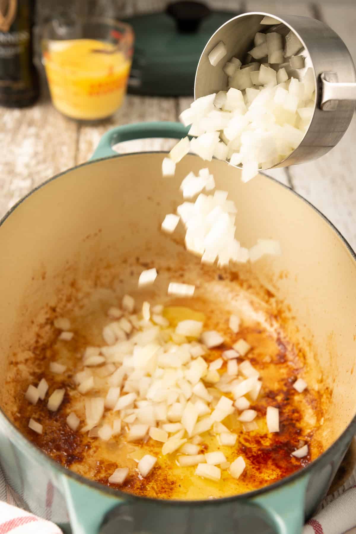 Diced onion being added to a Dutch oven to sauté.