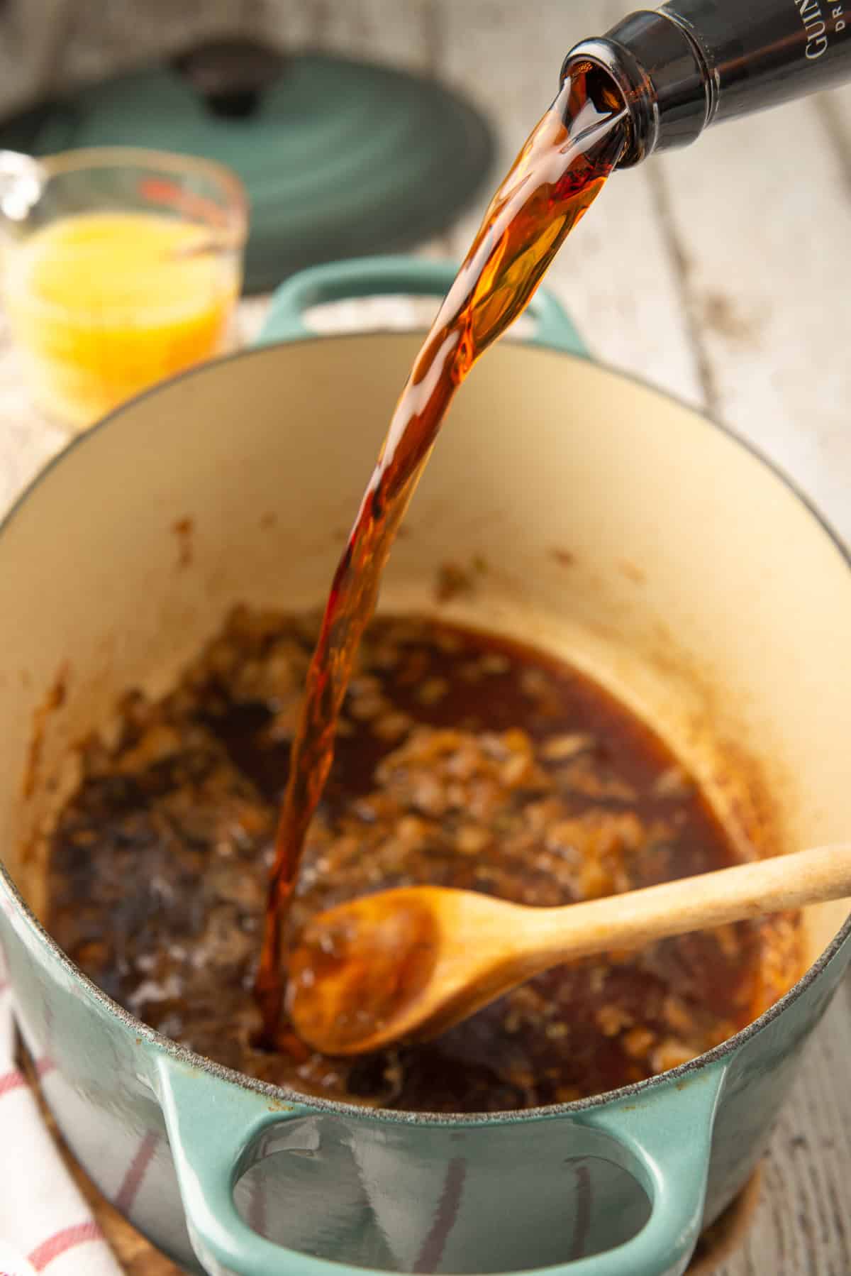 Beer being poured into a Dutch oven to deglaze the pan.