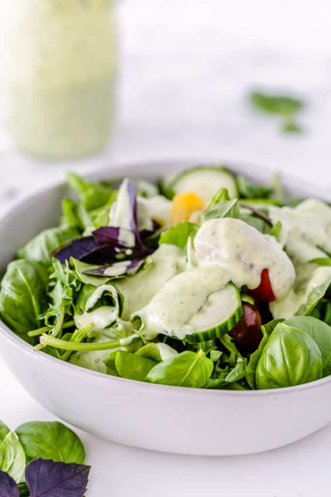 A white bowl filled with green salad 