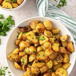 A white serving bowl filled with Lemon Roasted Greek Potatoes.