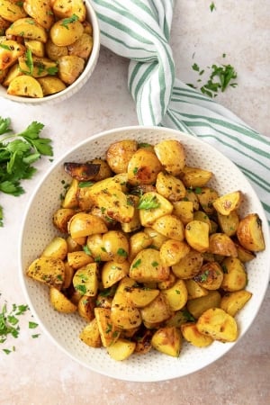 A white serving bowl filled with Lemon Roasted Greek Potatoes.