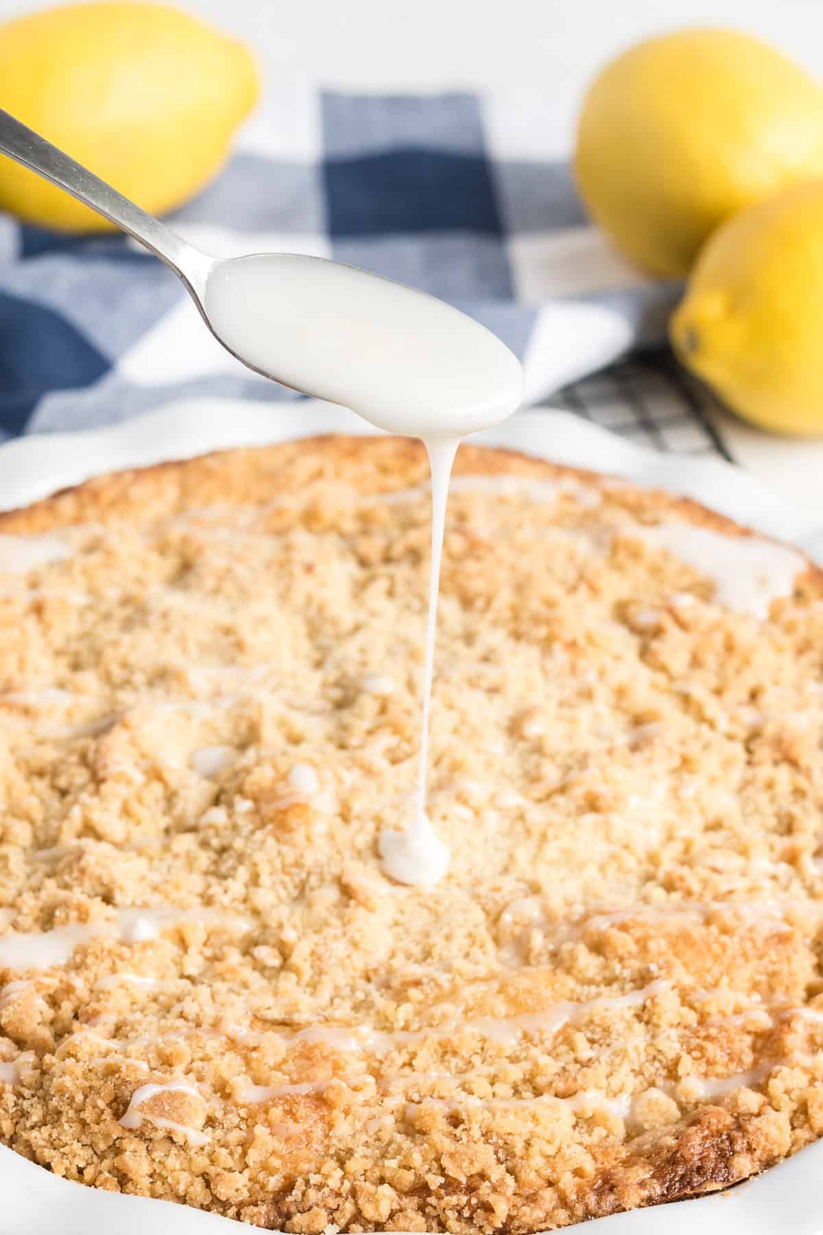 Lemon icing pours from a spoon on to the surface of the lemon zucchini cake.