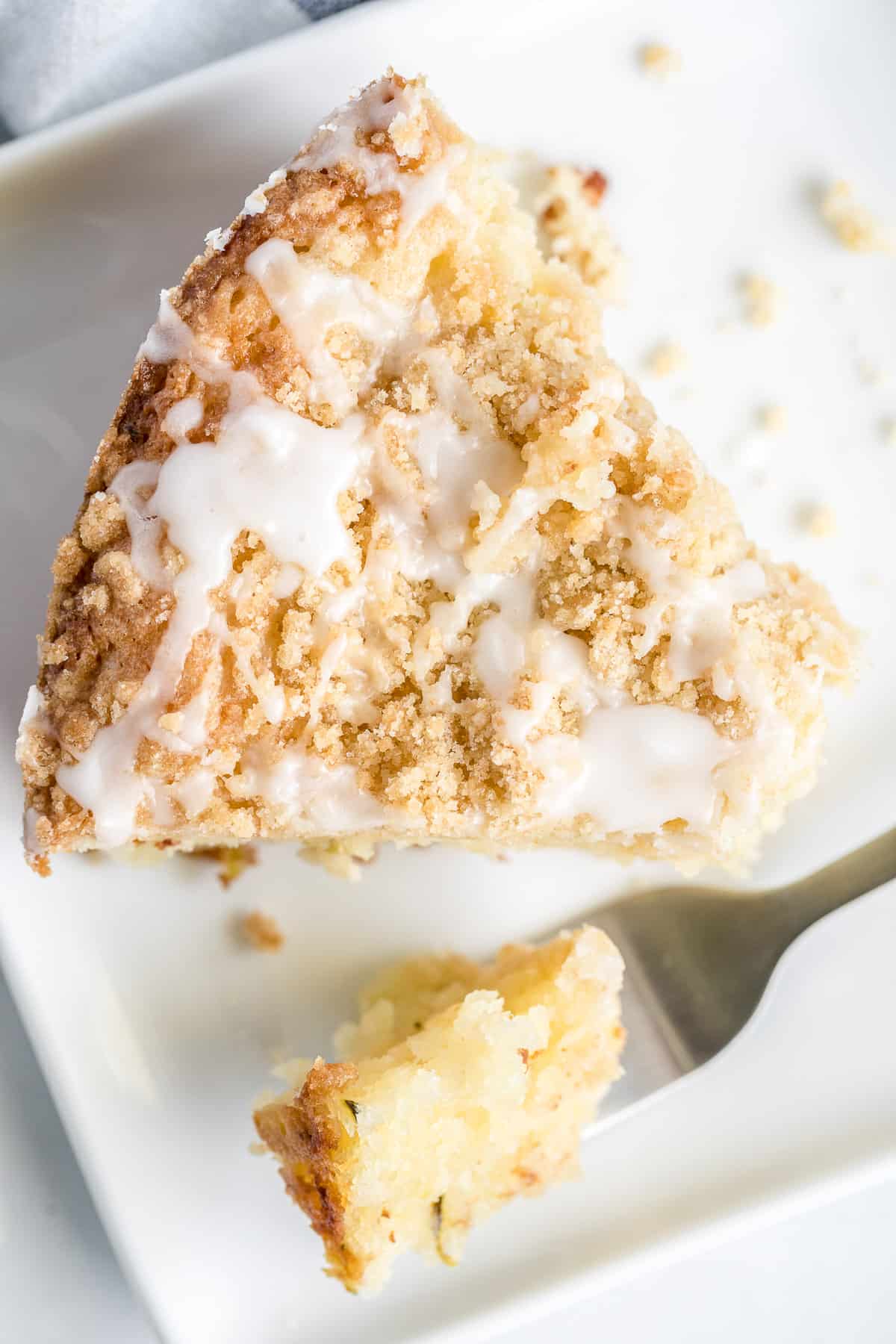 A slice of lemon zucchini cake with a fork on a white plate.