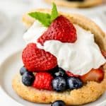 Shortcake stuffed with berries and whipped cream on a white plate.