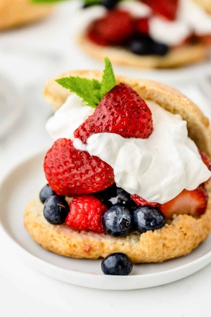 Shortcake stuffed with berries and whipped cream on a white plate.