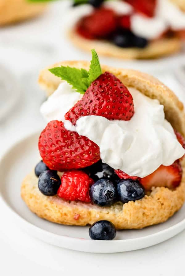 Shortcake stuffed with berries and whipped cream on a white plate.