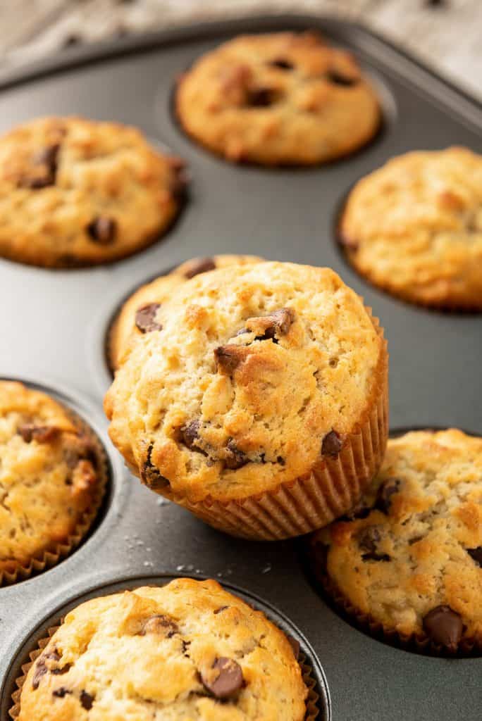 A muffin till full of Oatmeal Banana Muffins with one balanced on top.