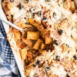 A spoon digs in to the center of the Pizza Pasta in a white casserole dish.