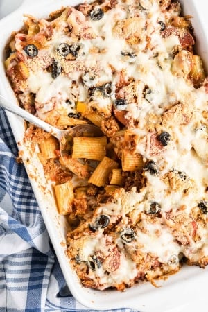 A spoon digs in to the center of the Pizza Pasta in a white casserole dish.