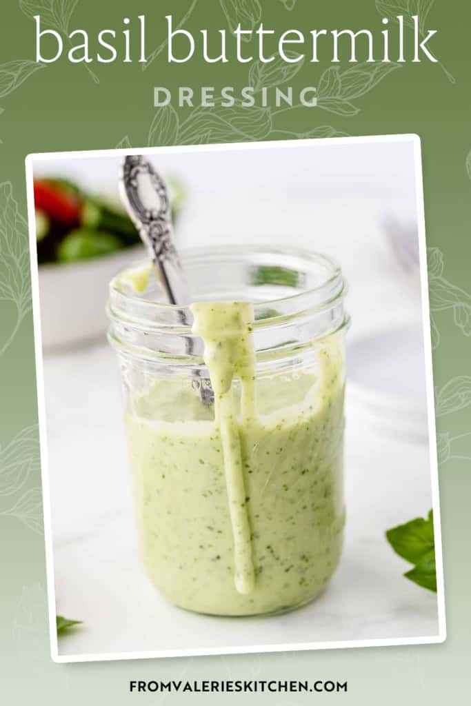 A spoon resting in a mason jar filled with basil buttermilk salad dressing with text overlay.