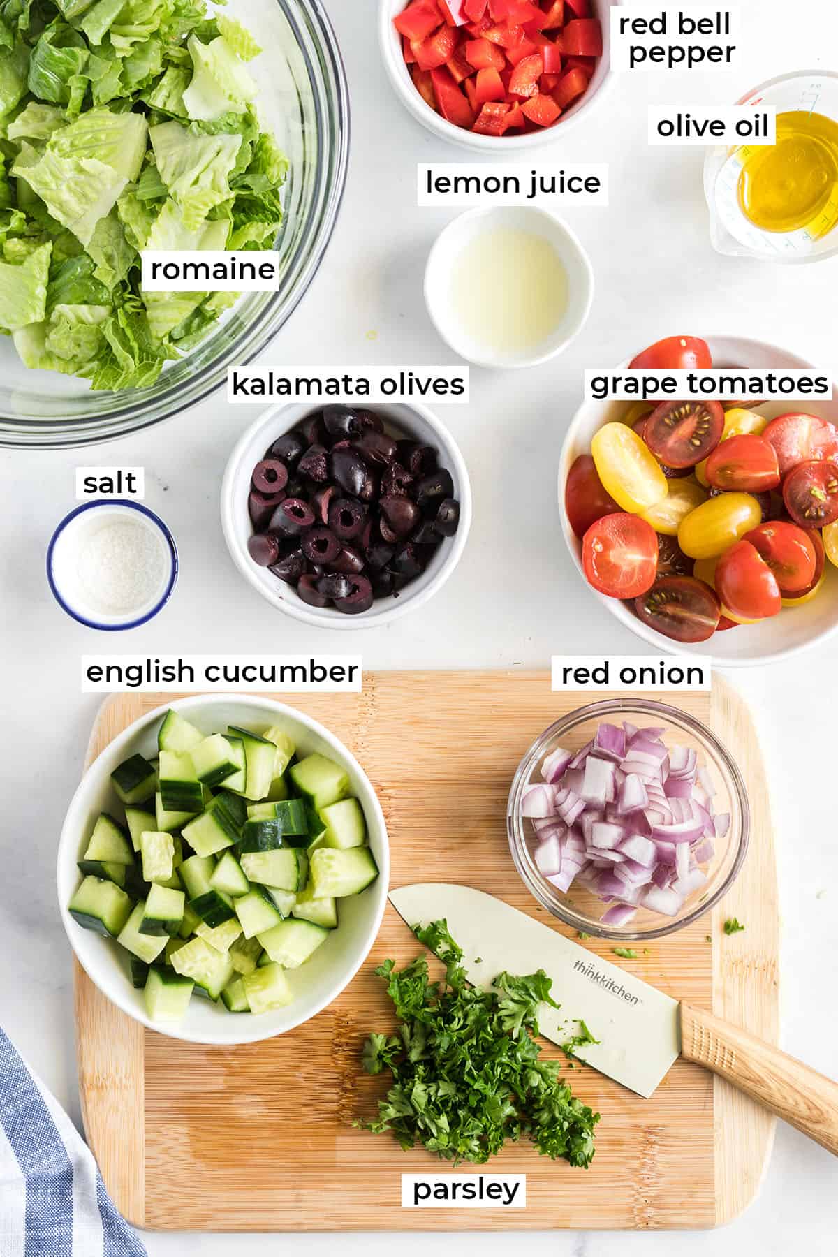 The ingredients for the Greek salad on a white counter with text overlay.