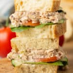 A Salmon Salad Sandwich with tomatoes and cucumber sliced in half and stacked.