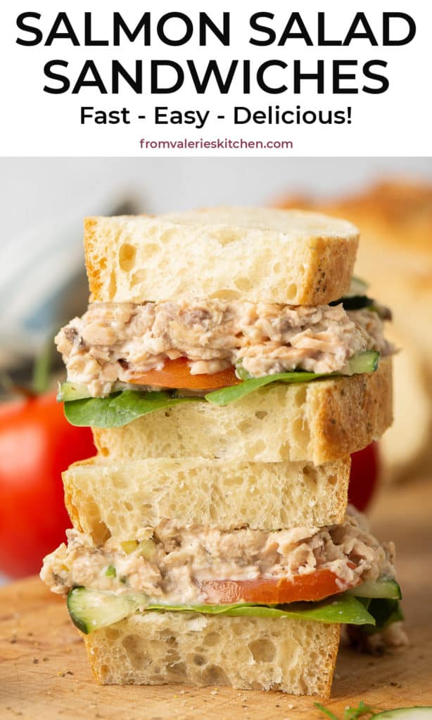 A salmon salad sandwich sliced in half and stacked on a wood cutting board with text overlay.