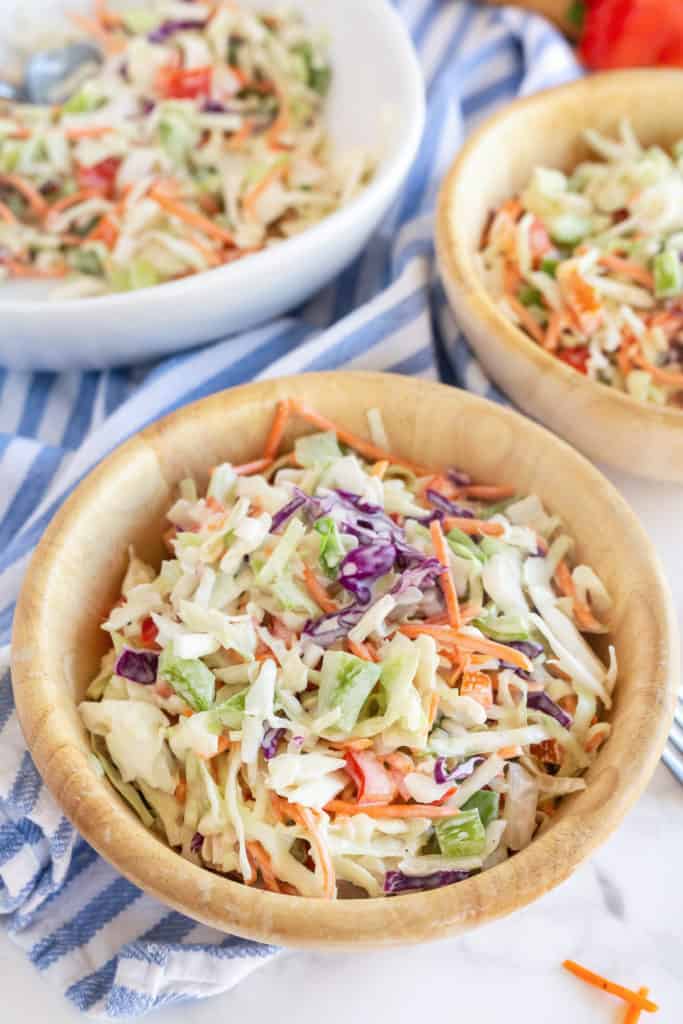A close up of a wooden bowl filled with coleslaw.