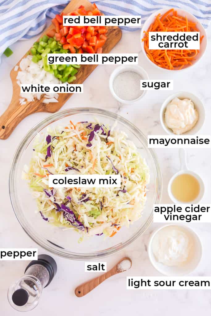 Coleslaw mix, bell peppers, onions and all the ingredients on a white surface.