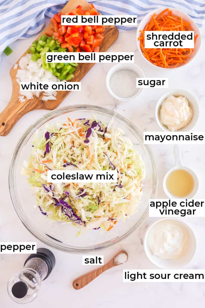 Coleslaw mix, bell peppers, onions and all the ingredients on a white surface.