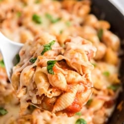 A spoon scoops Chicken Parmesan Pasta from a skillet.