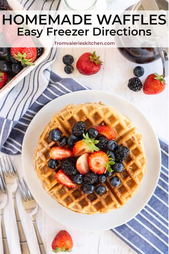 Waffles topped with berries on white plate on a blue and white striped cloth with text overlay.