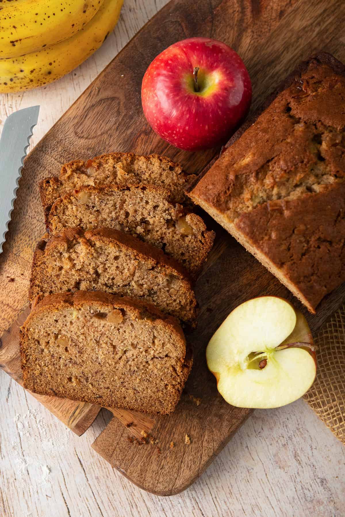 Slices of Apple Banana Bread on a cutting board with apples.
