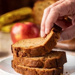 A hand lifting a slice from a stack of bread.