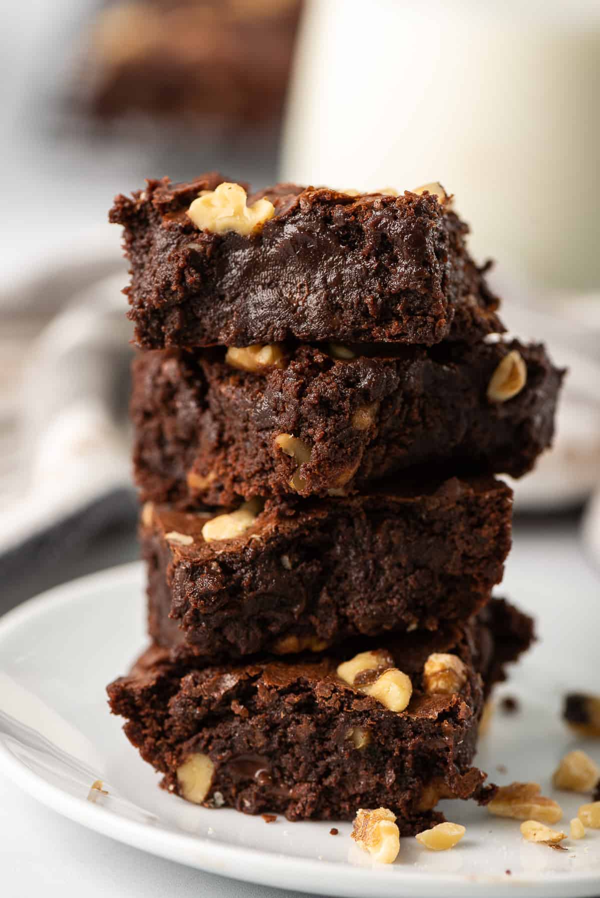 Three brownies stacked on a white plate.