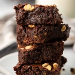 Three brownies stacked on a white plate.