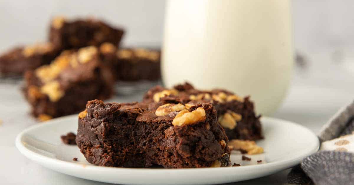 A brownie wiht a bite missing on a white plate.