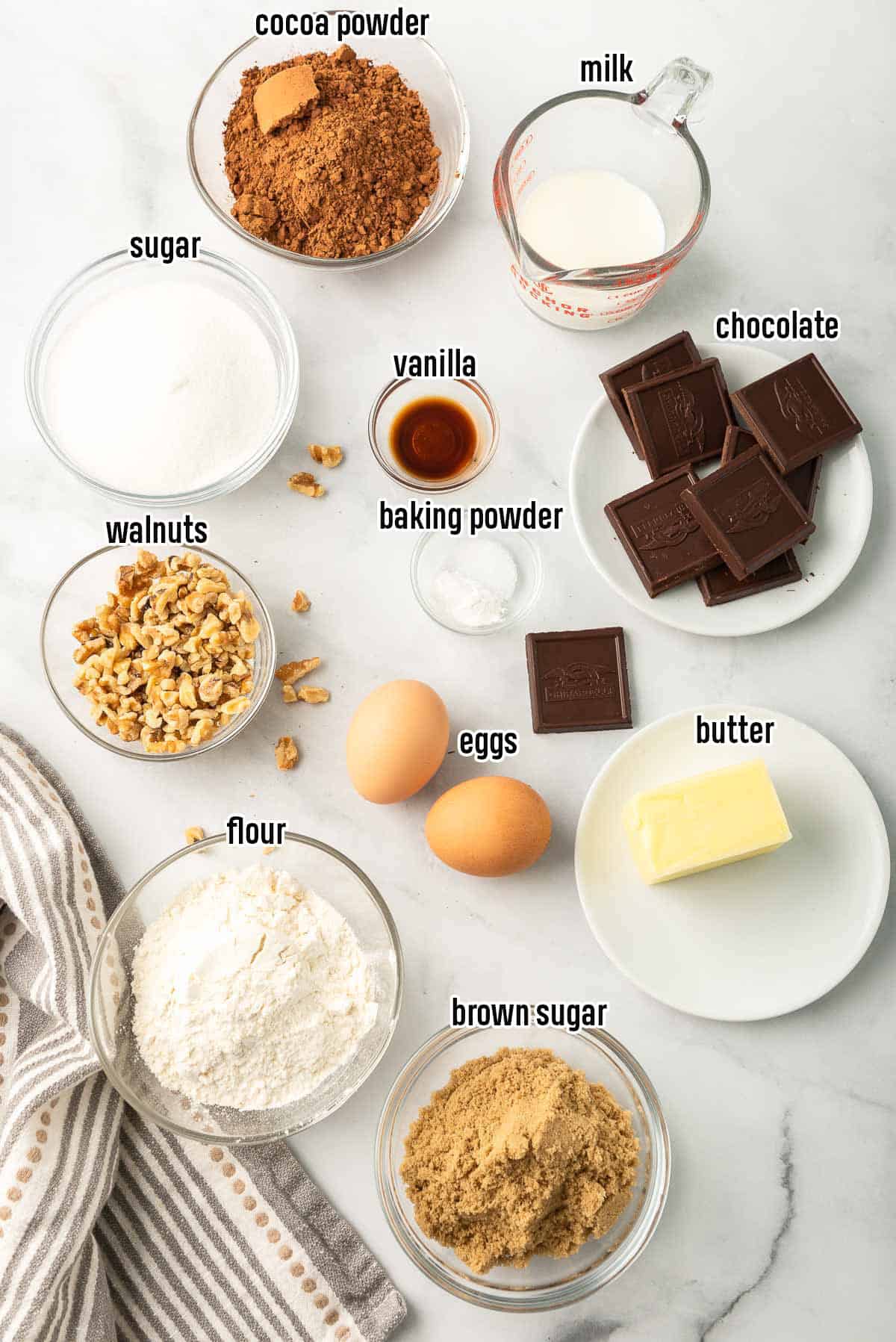 Flour, sugar, chocolate, and other brownie ingredients in bowls with text overlay.