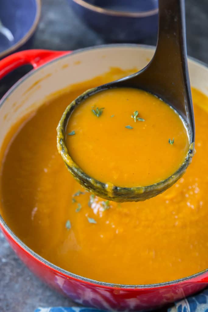 A ladle scoops soup from a pot.