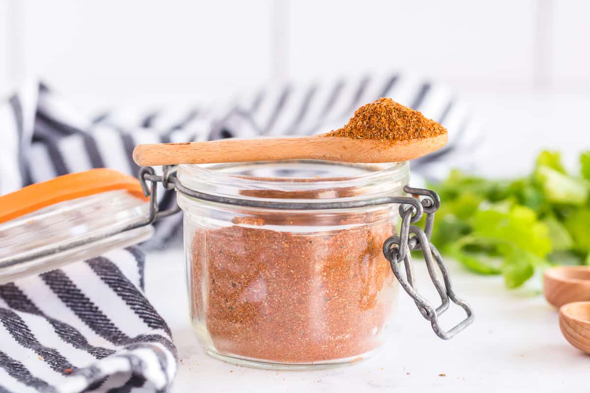A spoon rests on top of a jar of seasoning.
