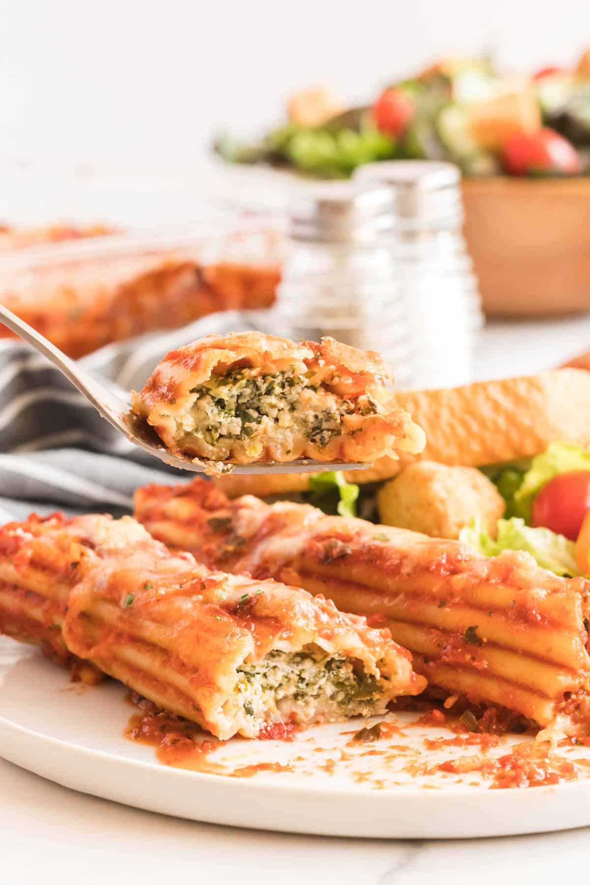 A fork lifts a bite of manicotti.